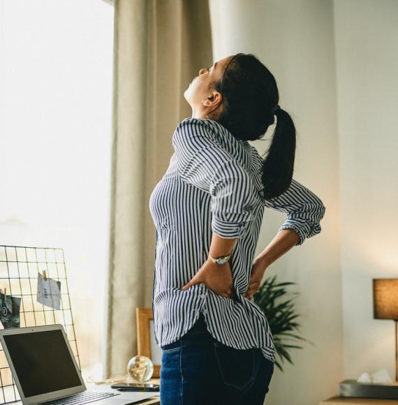 Image of a woman holding her lower back in pain depicting NICE's new recommendation of seven digital technologies