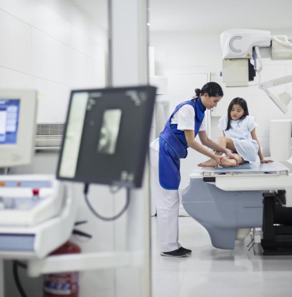 Girl having her leg scanned by an x-ray medical device