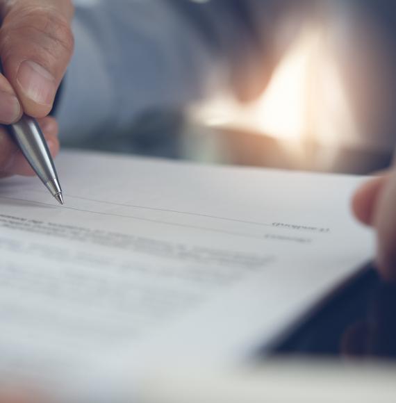 Image of a man signing a contract depicting the new deal for NHS consultants