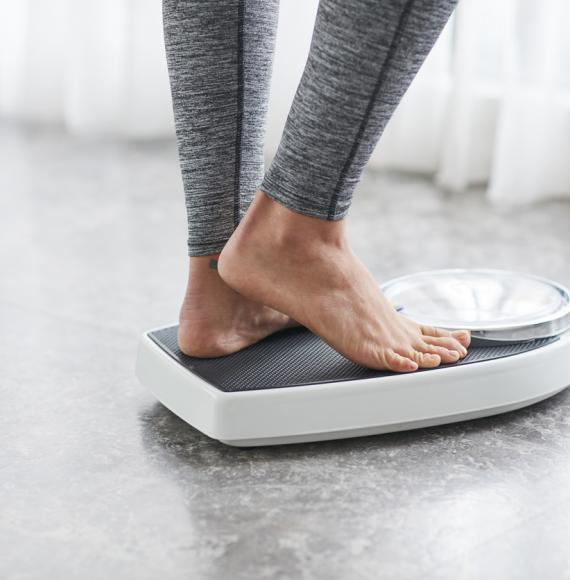 Woman standing on scales depicting weight loss
