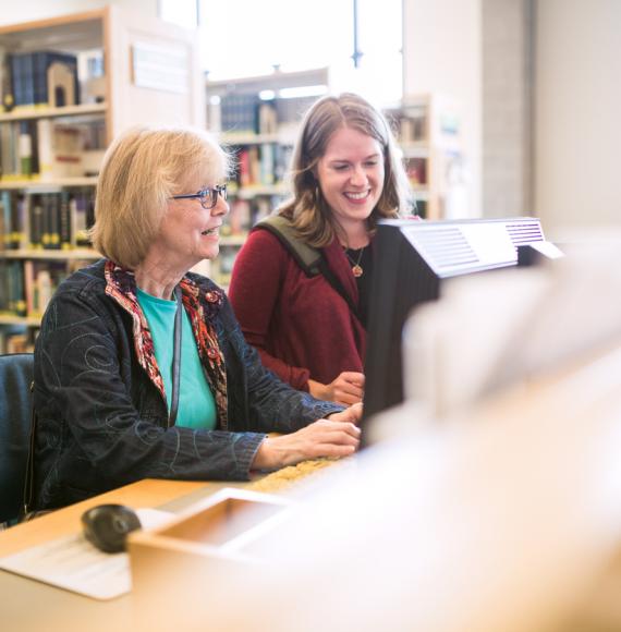 Older woman being helped by librarian to use a computer