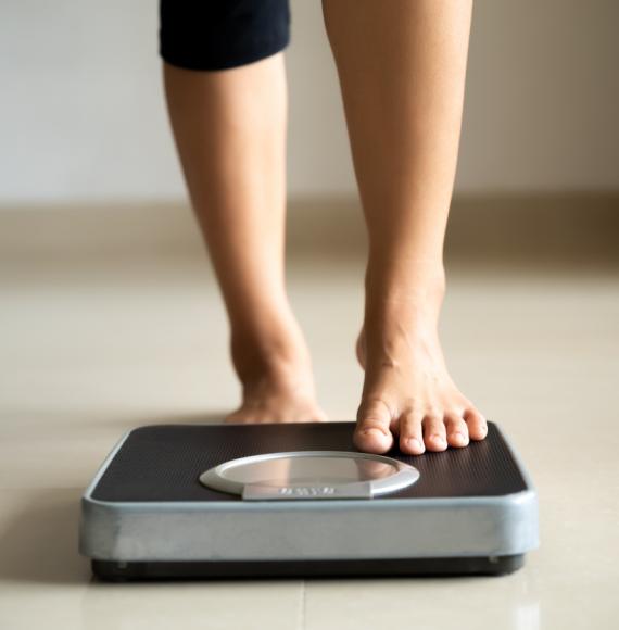 Female leg stepping on weigh scales