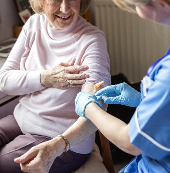 Elderly woman getting the flu jab in her home