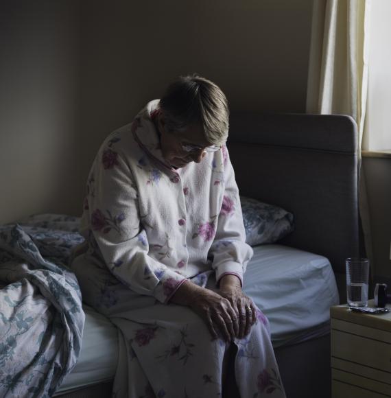 senior woman sitting on the side of her bed
