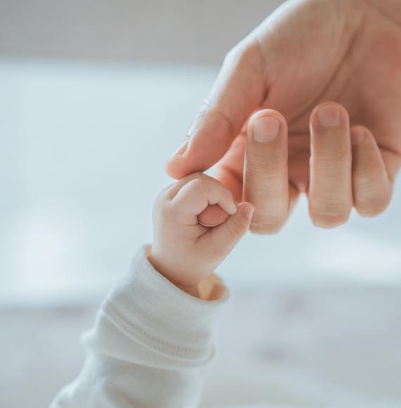 Newborn baby holding mothers finger