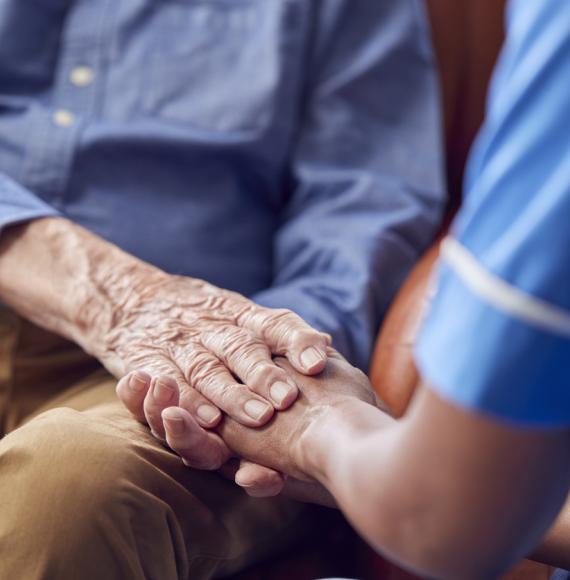 Female Care Worker Holding Hands Of Senior Man