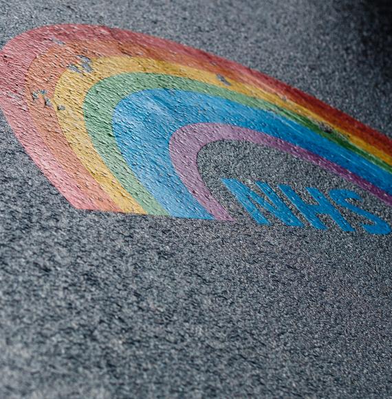Lgbt rainbow NHS logo painted on asphalt.