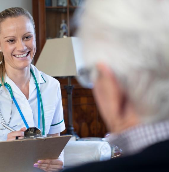 Nurse talking to senior man on home visit