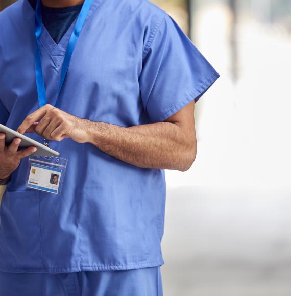 Male Medical Worker In Scrubs With Tablet