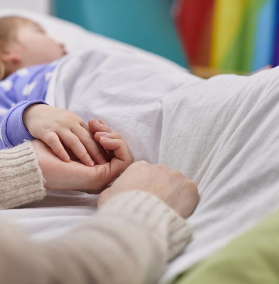 Mother and daughter holding hands in hospital