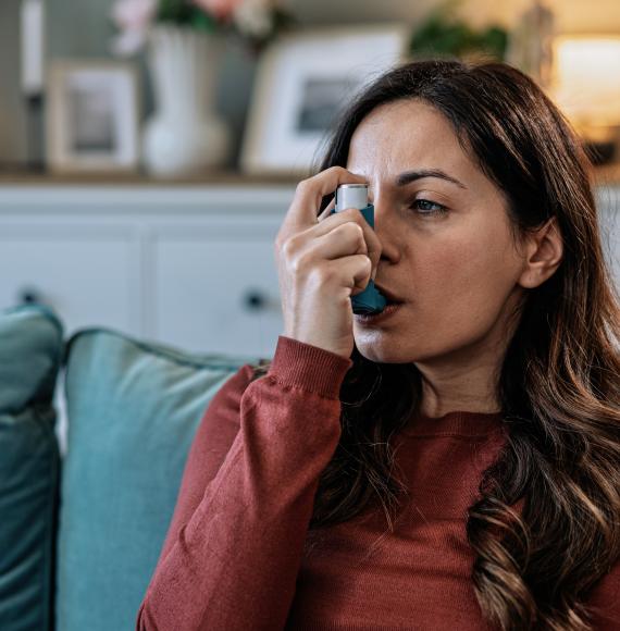 woman using her asthma inhaler at home